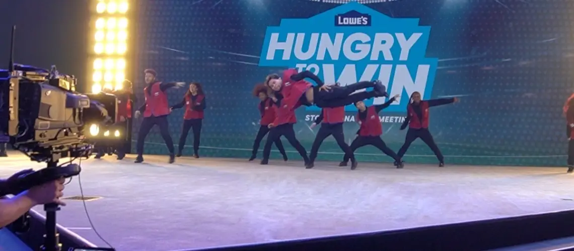 Professional Las Vegas dance company performing a high-energy choreographed routine on stage for a corporate event, featuring a synchronized dance crew in branded entertainment production